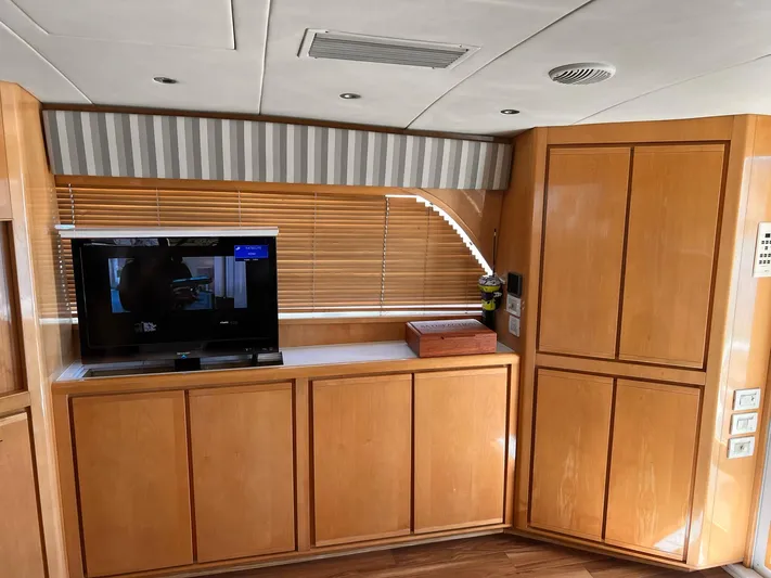 Satisfaction Yacht Photos Pics Interior of a 1999 Bertram 60 Convertible yacht with wooden cabinets and a TV.
