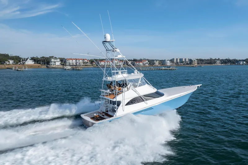 Reel Developers Yacht Photos Pics 2009 Viking 60 Convertible yacht cruising on open water near coastal buildings.