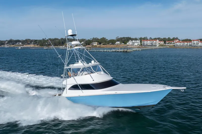 Reel Developers Yacht Photos Pics 2009 Viking 60 Convertible yacht cruising on open water near coastal buildings.