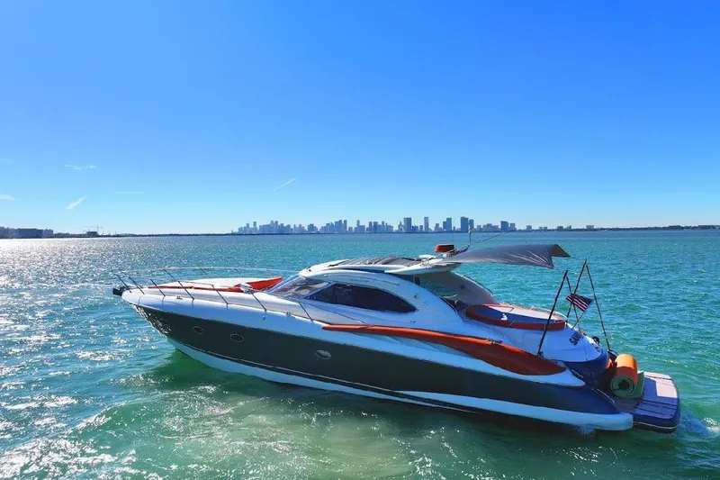  Yacht Photos Pics Sunseeker Predator 60 yacht cruising on clear waters with city skyline in background.