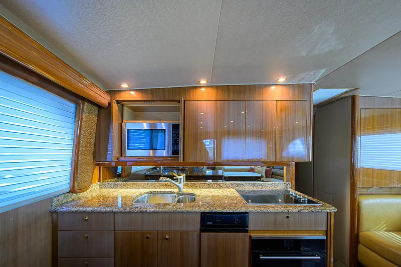 Don't Stop Believing Yacht Photos Pics Luxurious kitchen interior of a 2007 Viking 68 Convertible yacht with wood cabinetry and granite countertops.
