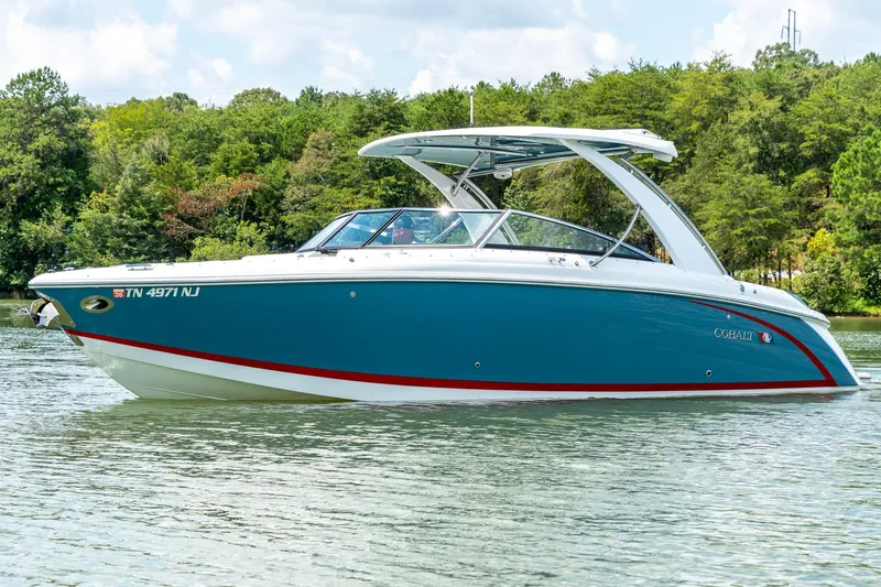  Yacht Photos Pics 2023 Cobalt R30 boat on a serene lake with lush green trees.