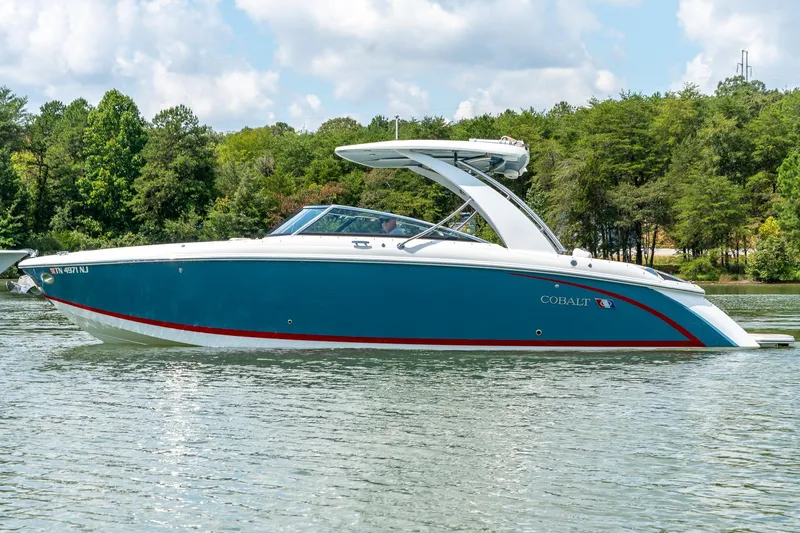  Yacht Photos Pics 2023 Cobalt R30 boat on a serene lake with lush green trees.