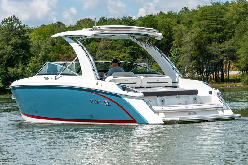  Yacht Photos Pics 2023 Cobalt R30 boat on a serene lake, surrounded by lush greenery.