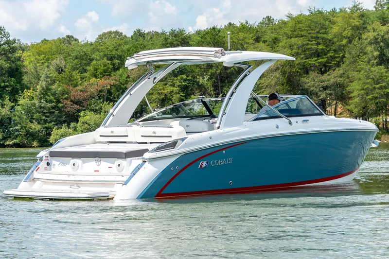  Yacht Photos Pics 2023 Cobalt R30 boat cruising on a serene lake with lush green trees.