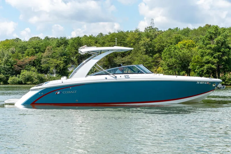  Yacht Photos Pics 2023 Cobalt R30 boat cruising on a serene lake with lush green trees.