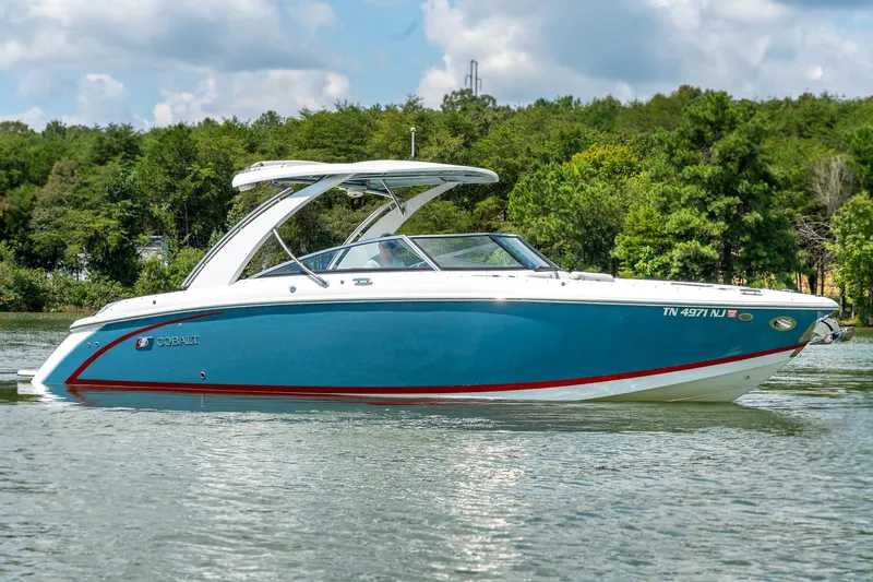  Yacht Photos Pics 2023 Cobalt R30 boat on a serene lake with lush green trees.