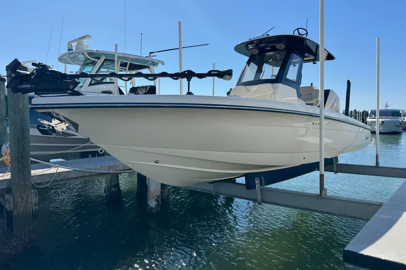  Yacht Photos Pics 2025 Scout 281 XSS boat docked on lift, sunny marina background.