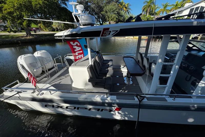  Yacht Photos Pics 2017 Axopar 37 Sun Top boat with seating, table, and twin engines, docked by a canal.