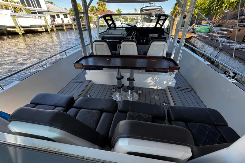  Yacht Photos Pics 2017 Axopar 37 Sun Top boat interior with seating and table, docked by waterfront homes.