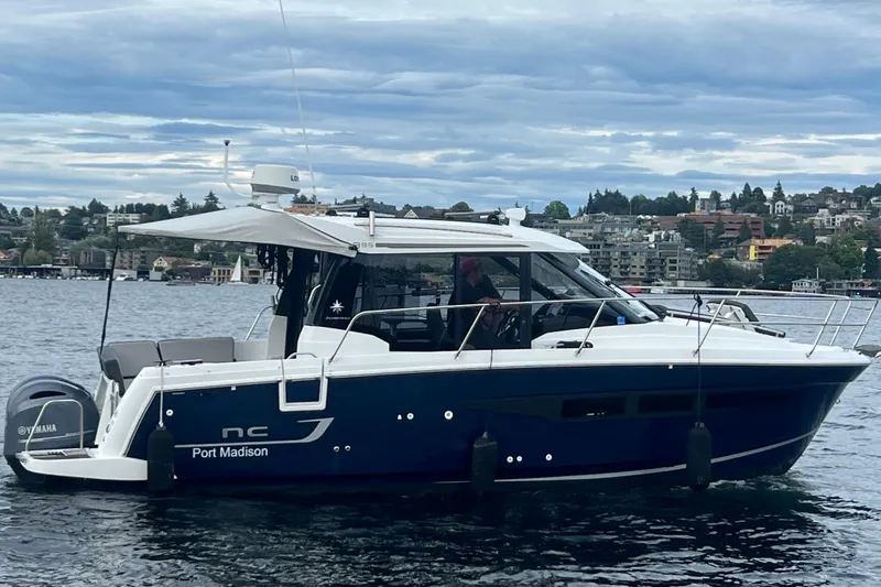  Yacht Photos Pics 2018 Jeanneau NC 895 boat on water, cityscape background, overcast sky.