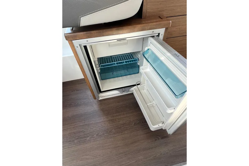  Yacht Photos Pics Open refrigerator inside 2018 Jeanneau NC 895 boat, featuring wooden flooring and modern design.