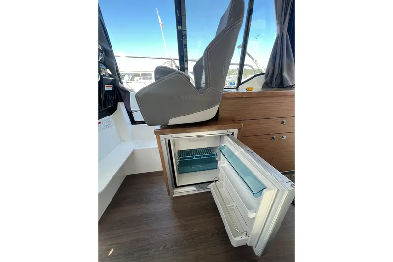  Yacht Photos Pics Interior of 2018 Jeanneau NC 895 boat with open refrigerator and helm seat.