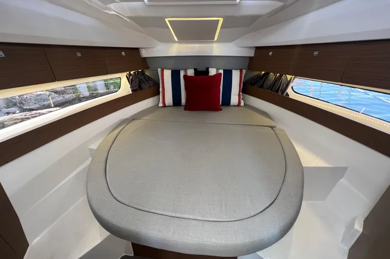  Yacht Photos Pics 2018 Jeanneau NC 895 cabin interior with cozy bed and nautical-themed pillows.