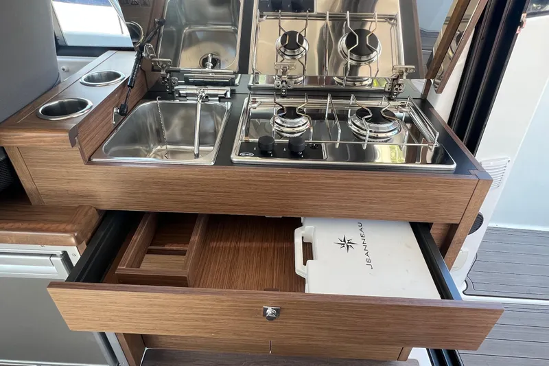  Yacht Photos Pics Compact kitchen area in 2018 Jeanneau NC 895 boat with stove, sink, and storage.