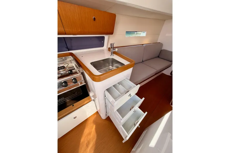 First 36 Yacht Photos Pics 2023 Beneteau First 36 yacht interior with kitchen, sink, stove, and seating area.