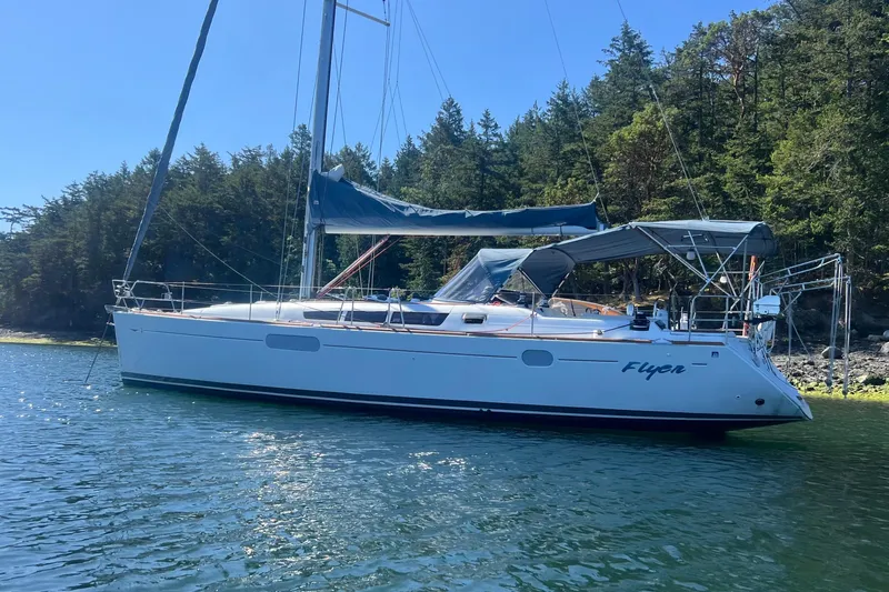 Flyer Yacht Photos Pics 2010 Jeanneau Sun Odyssey 44i sailboat anchored near forested shoreline.