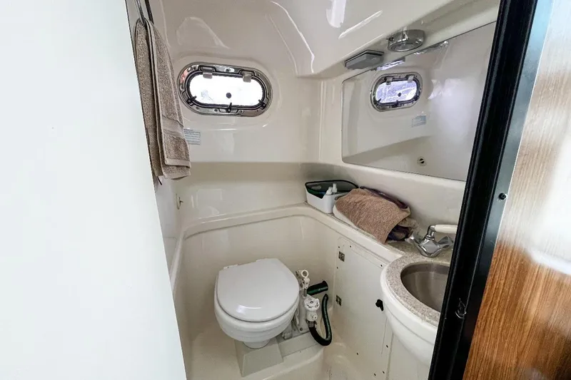  Yacht Photos Pics 2014 Pursuit OS 285 Offshore boat bathroom with toilet, sink, and porthole window.