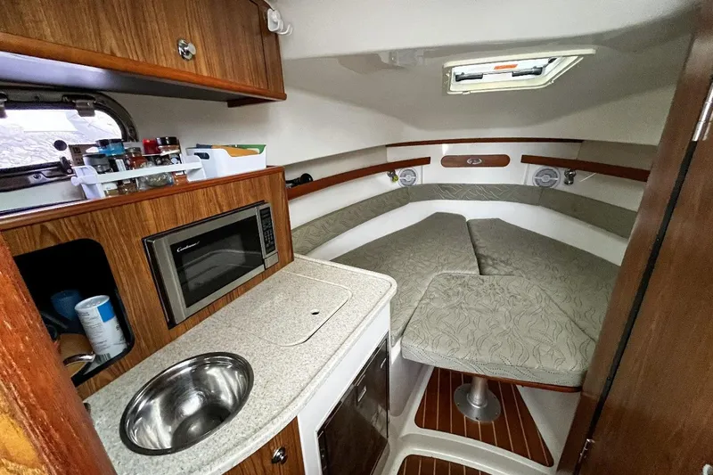  Yacht Photos Pics 2014 Pursuit OS 285 Offshore cabin with kitchenette, microwave, and cozy seating area.