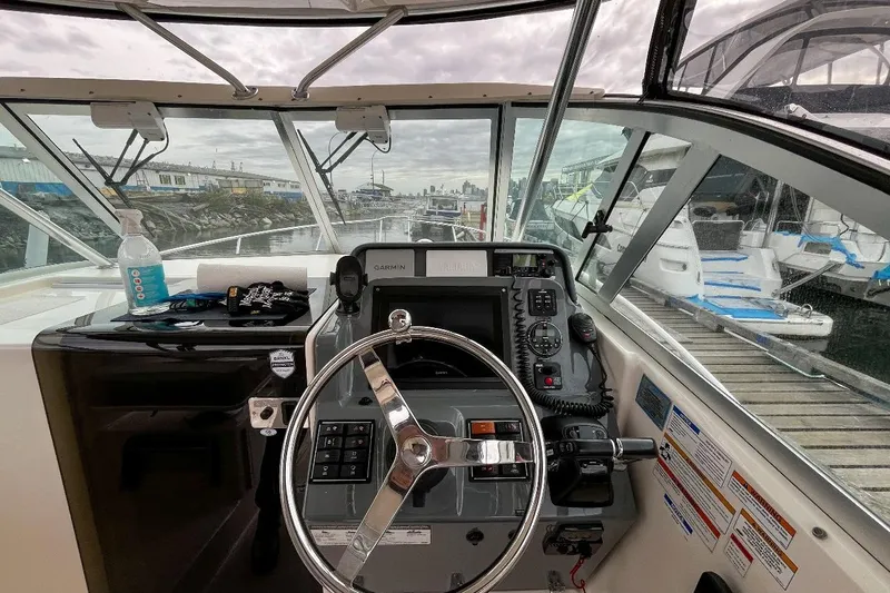  Yacht Photos Pics 2014 Pursuit OS 285 Offshore boat cockpit with steering wheel and navigation equipment.