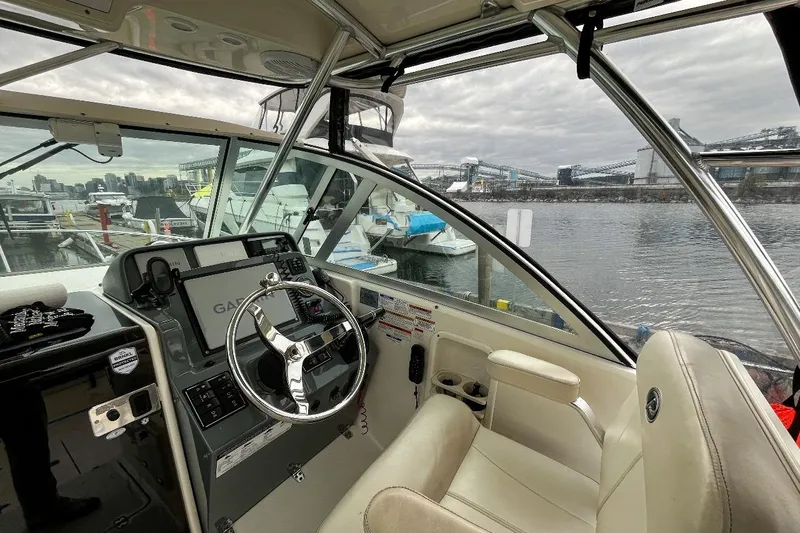  Yacht Photos Pics Interior view of 2014 Pursuit OS 285 Offshore boat cockpit with steering wheel and navigation system.