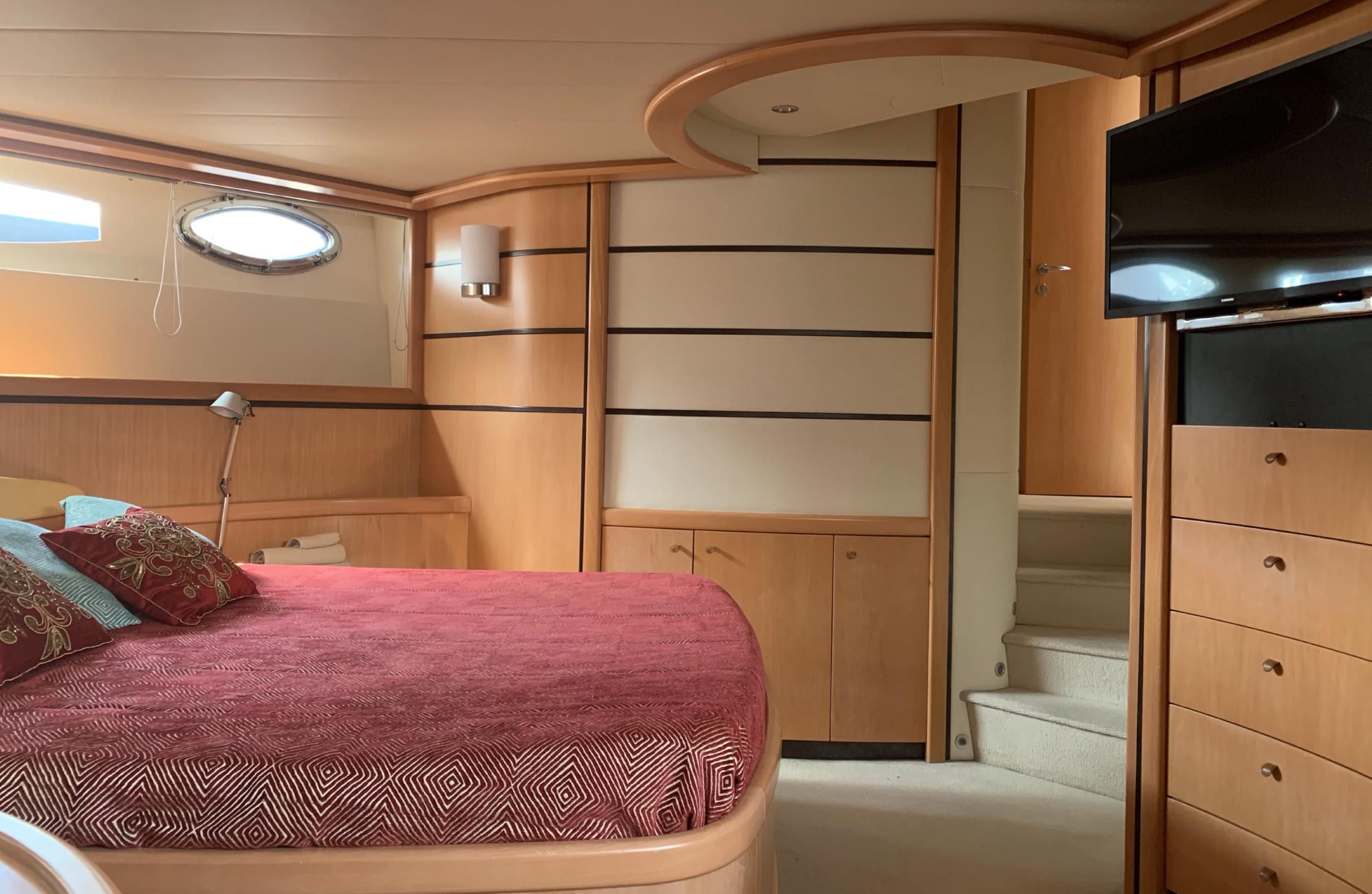 Luxurious 2005 Pershing 76 yacht bedroom with elegant wood paneling and modern furnishings.
