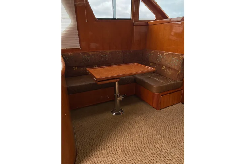  Yacht Photos Pics Interior of 2012 Mikelson 43 Sportfisher with wooden table and cushioned seating.