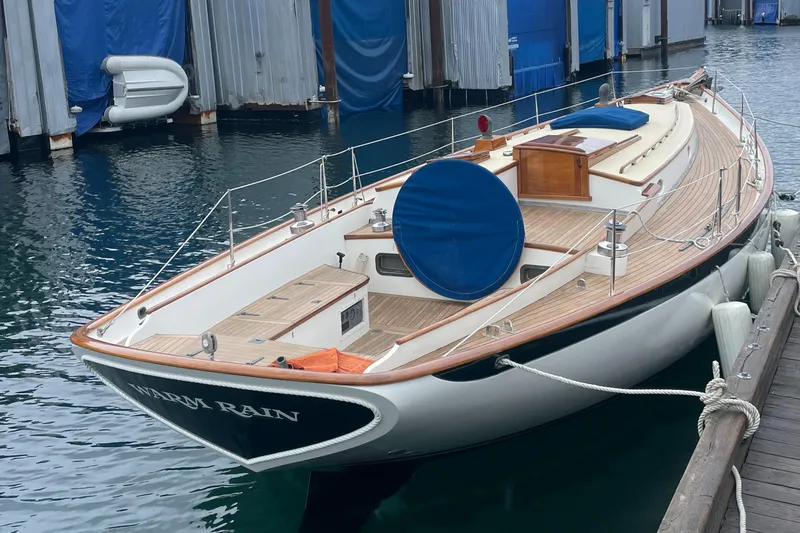 "warm Rain Ii" Yacht Photos Pics Custom Bruce King 1992 sailboat docked, featuring wooden deck and blue covers.