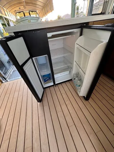 Yacht Photos Pics Open mini fridge on 2014 Cruisers Yachts 45 Cantius Black Diamond, showing interior shelves and bottled water.