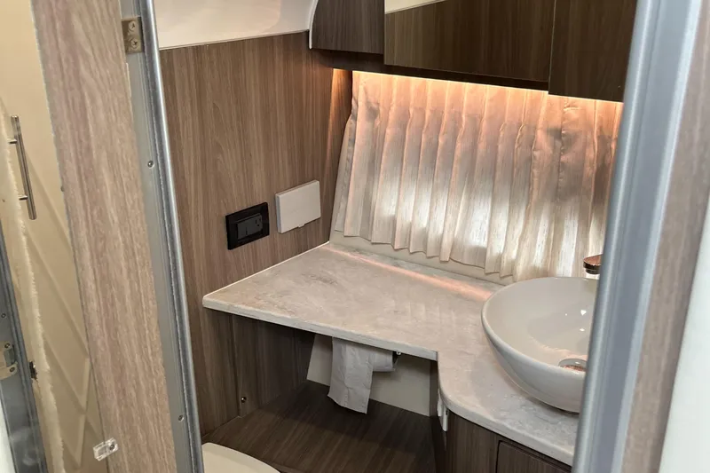 Don't Stop Believin Yacht Photos Pics 2022 Regal 33 SAV bathroom with modern sink, wood paneling, and ambient lighting.