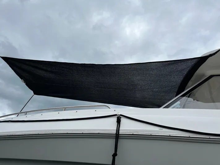 Don't Stop Believin Yacht Photos Pics 2022 Regal 33 SAV boat with black sunshade under cloudy sky.