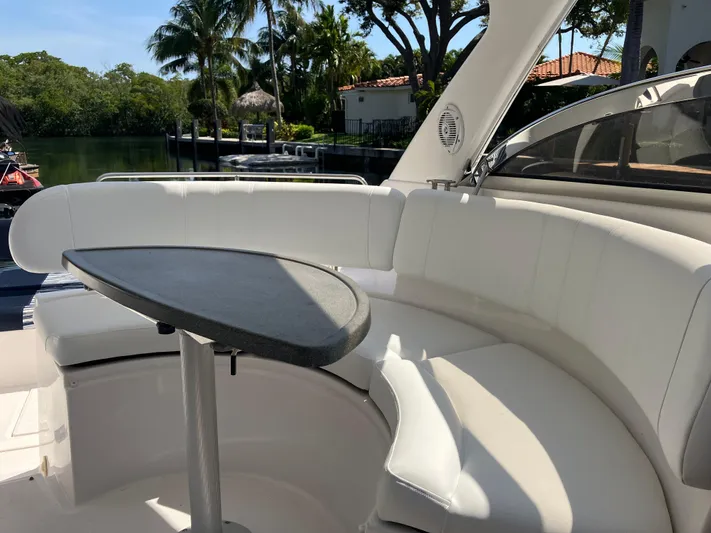  Yacht Photos Pics 2007 Regal 3760 Commodore yacht with white seating and table, docked near lush greenery.