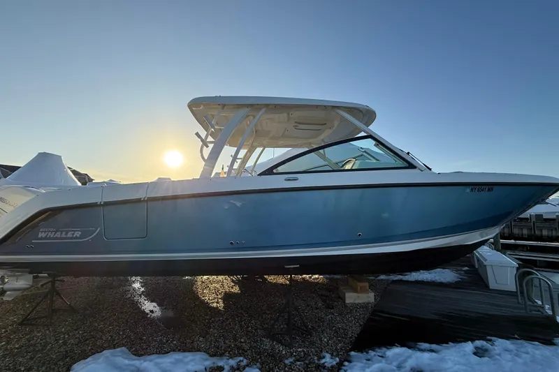  Yacht Photos Pics 2017 Boston Whaler 320 Vantage boat in sunlight, docked on a snowy shore.