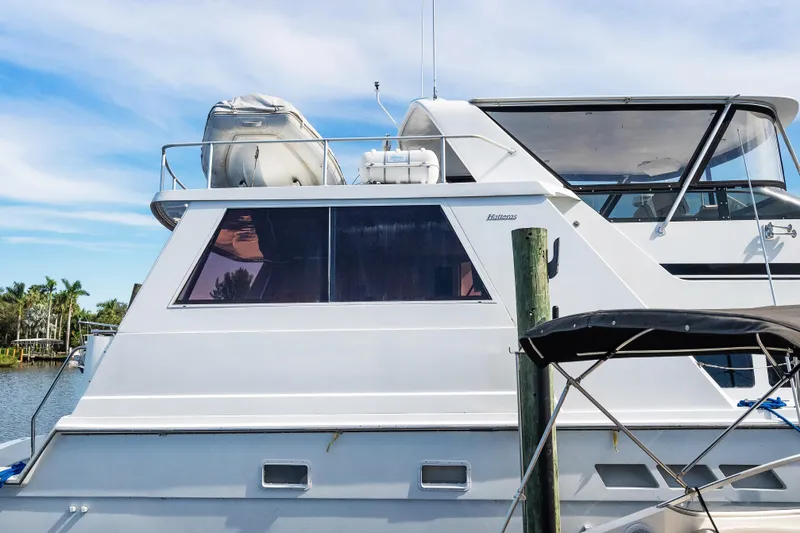  Yacht Photos Pics 1999 Hatteras 52 Cockpit Motor Yacht docked, featuring sleek design and spacious upper deck.