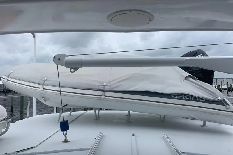  Yacht Photos Pics 1999 Hatteras 52 Cockpit Motor Yacht with covered dinghy on deck, cloudy sky background.