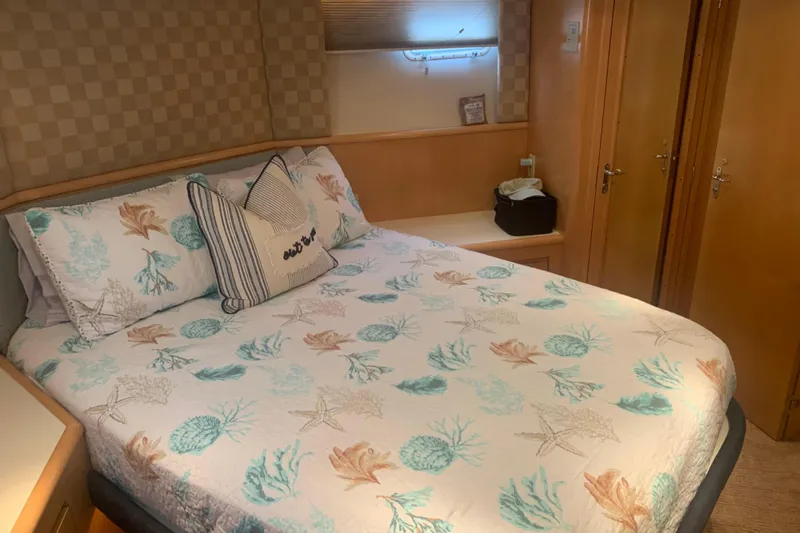  Yacht Photos Pics Cozy bedroom in 1999 Hatteras 52 Cockpit Motor Yacht with nautical-themed bedding.