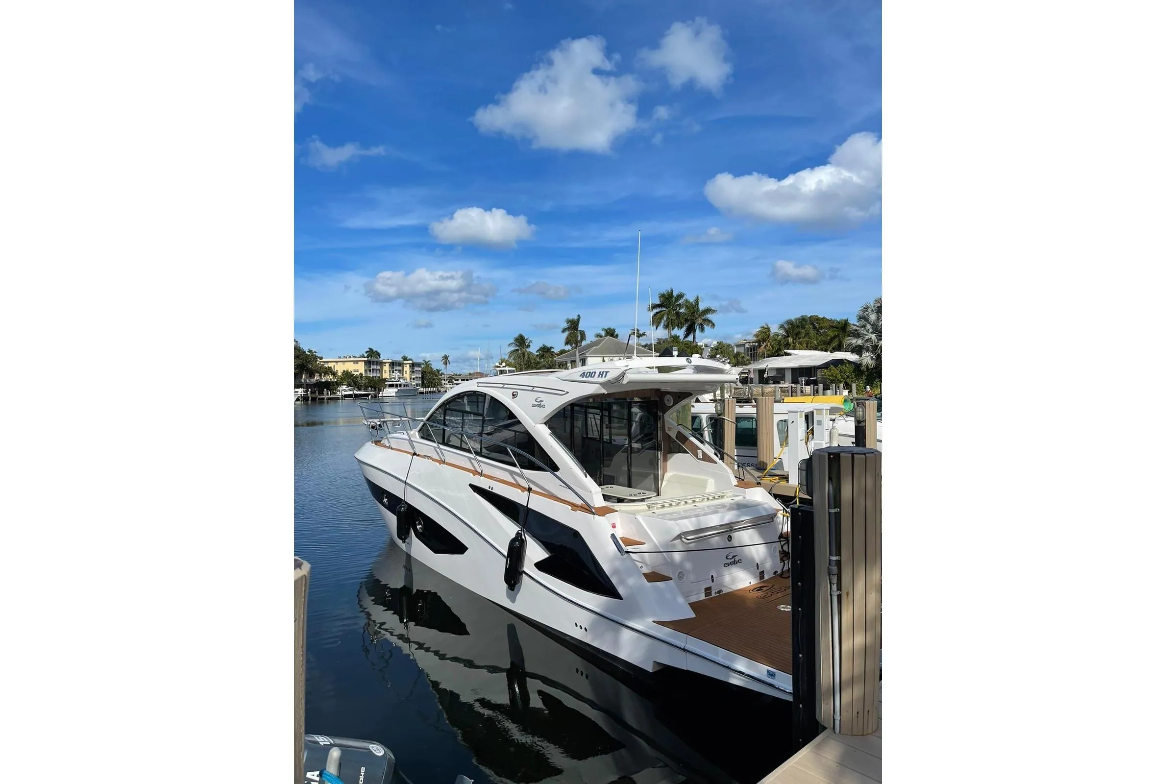 2023 Evolve 400HT yacht docked in a sunny marina with palm trees.