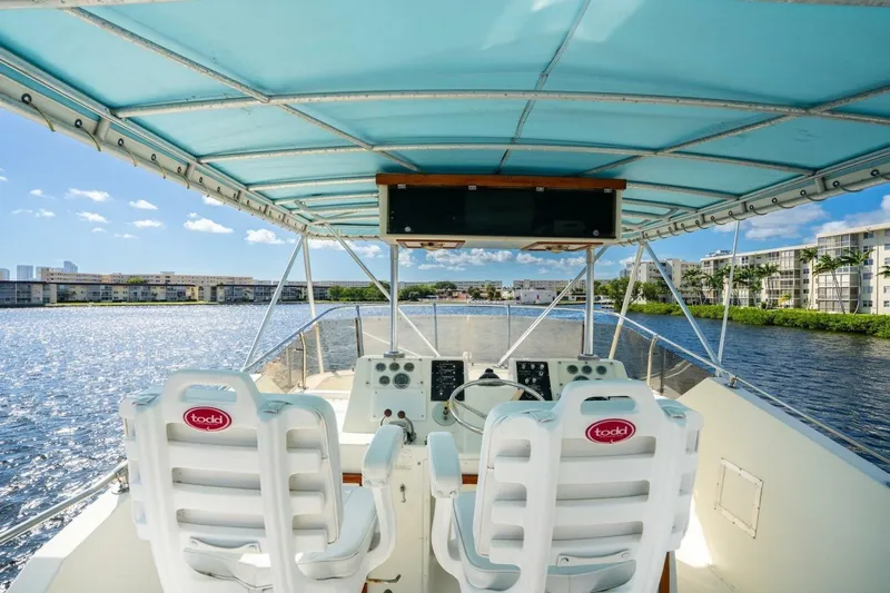 Dharma Yacht Photos Pics 1978 Hatteras 53 Yacht Fisherman helm with blue canopy, overlooking waterfront buildings.