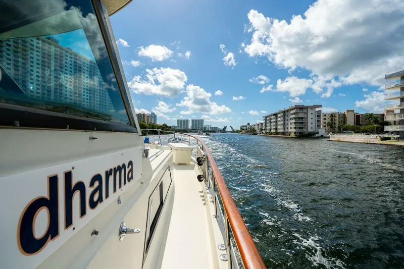Dharma Yacht Photos Pics 1978 Hatteras 53 Yacht Fisherman cruising through a scenic urban waterway.