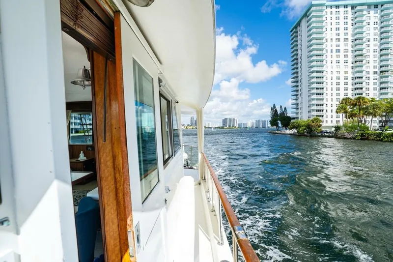 Dharma Yacht Photos Pics 1978 Hatteras 53 Yacht Fisherman cruising near waterfront high-rise buildings.