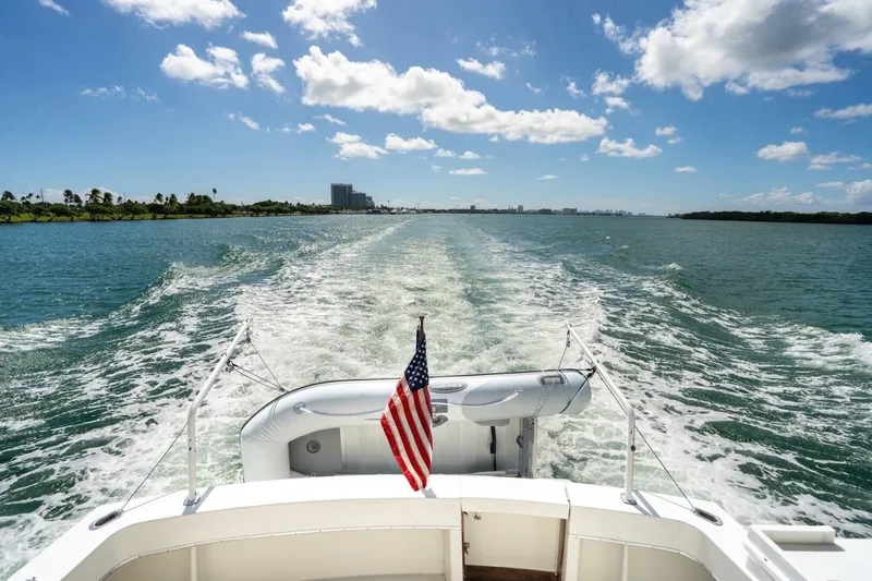 Dharma Yacht Photos Pics 1978 Hatteras 53 Yacht Fisherman cruising on open water under a clear blue sky.