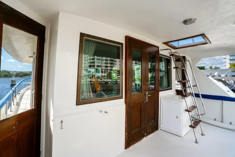 Dharma Yacht Photos Pics 1978 Hatteras 53 Yacht Fisherman deck with wooden doors and ladder, docked by waterfront.