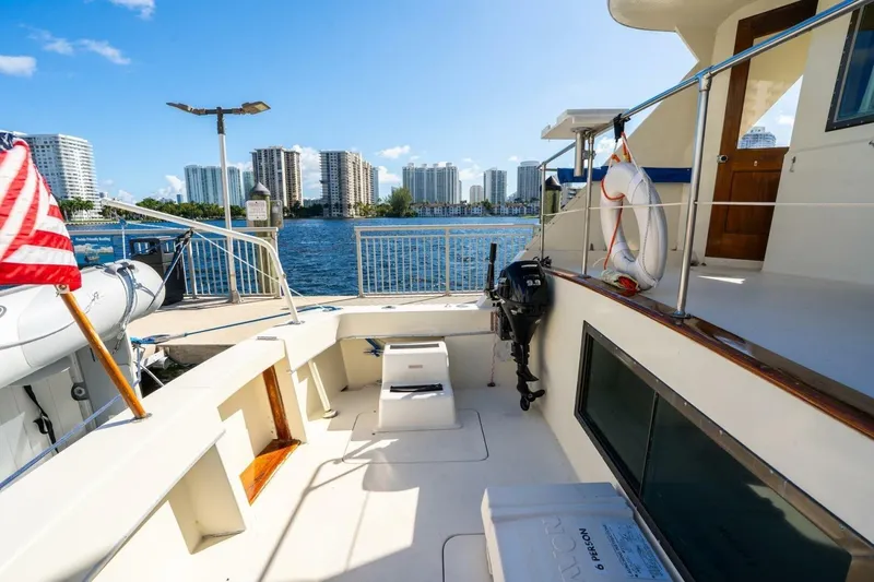Dharma Yacht Photos Pics 1978 Hatteras 53 Yacht Fisherman docked, with city skyline and American flag.