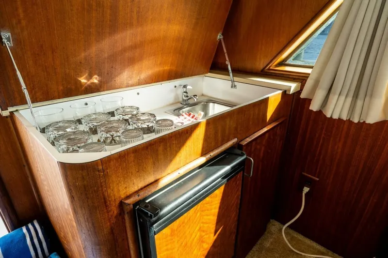 Dharma Yacht Photos Pics 1978 Hatteras 53 Yacht Fisherman interior with sink, glasses, and wooden cabinetry.