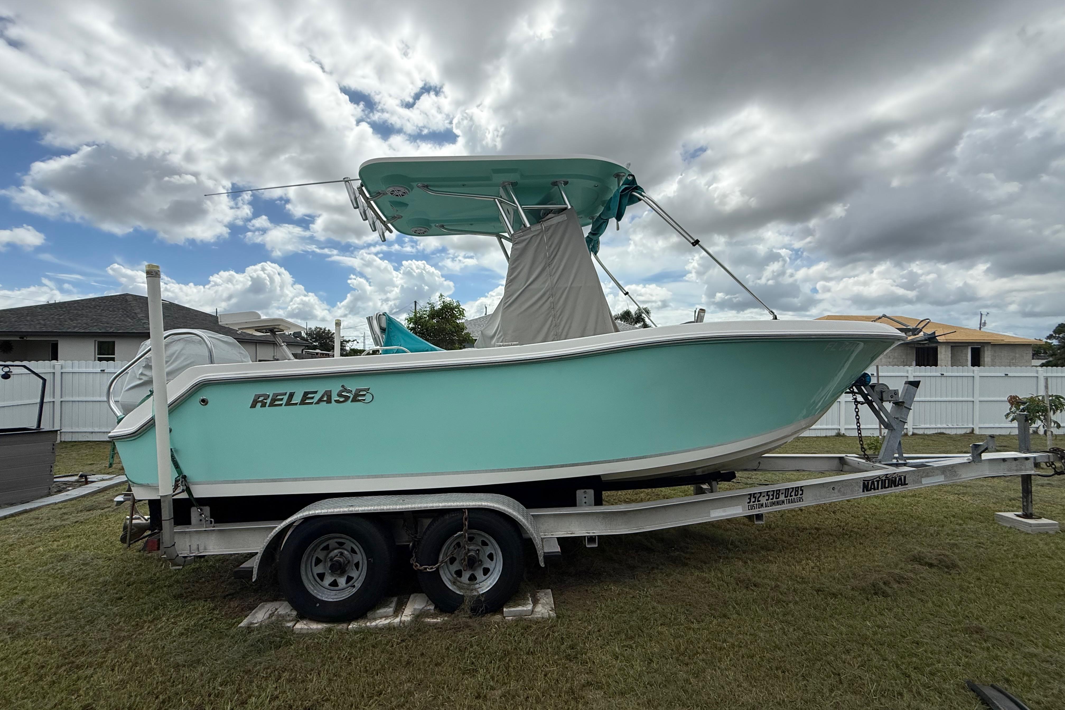 2018 Release 208 RX boat on trailer, parked on grass under cloudy sky.