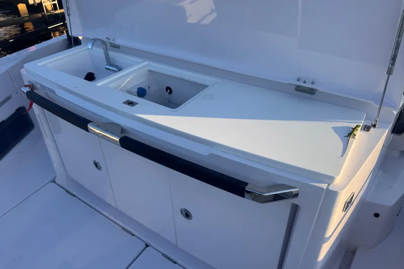Axopar 37 Suntop Yacht Photos Pics 2024 Axopar 37 SunTop boat sink and storage area, featuring sleek design.