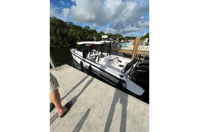 Axopar 37 Suntop Yacht Photos Pics 2024 Axopar 37 SunTop boat docked by a scenic riverside under a partly cloudy sky.