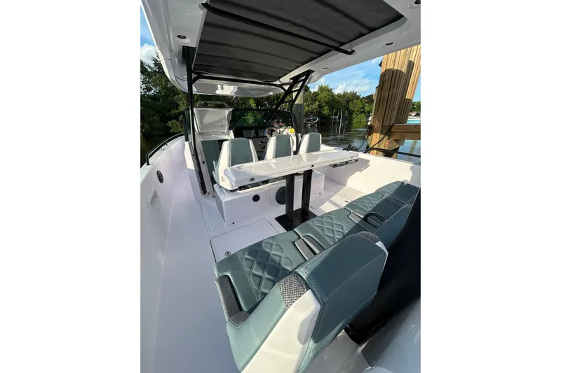 Axopar 37 Suntop Yacht Photos Pics 2024 Axopar 37 SunTop boat interior with seating and table, docked by water.