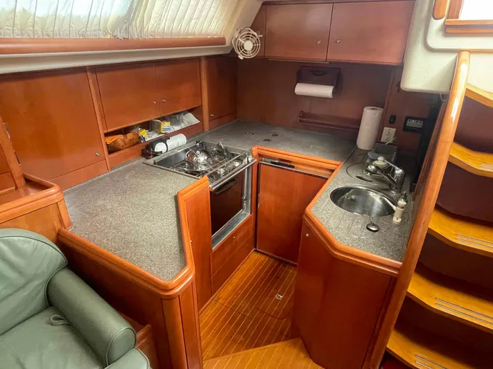 Gratitude Yacht Photos Pics Cozy kitchen area in a 1999 Moody 46 CC yacht with wooden cabinetry and compact appliances.