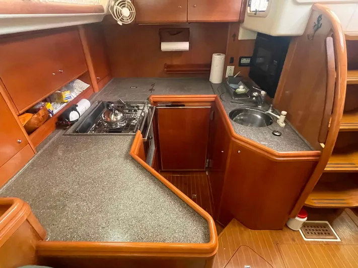 Gratitude Yacht Photos Pics Cozy kitchen area in a 1999 Moody 46 CC sailboat with wooden cabinetry and compact appliances.